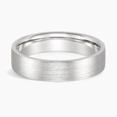 a white gold wedding ring on a plain surface