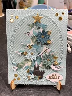 a handmade christmas card with a tree and stars on the top, sitting on a table