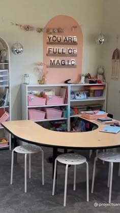 there is a table and chairs in the room with pink bins on the wall