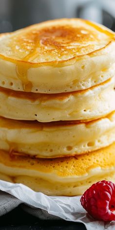 a stack of pancakes with syrup and raspberries