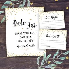 two save the date cards with gold dots on them and greenery in front of them