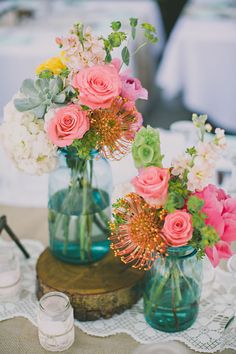 two vases filled with flowers sitting on top of a table