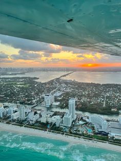 an aerial view of a city and the ocean at sunset from a plane in flight