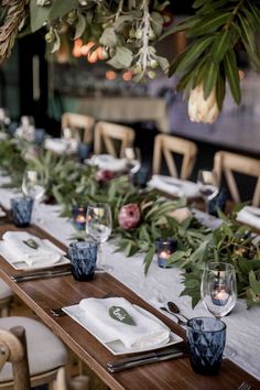 a long table set with place settings and greenery