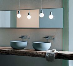 two sinks are shown in front of a mirror with three lights hanging above the sink