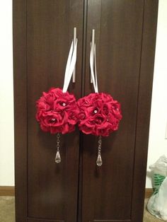 two red flowers are attached to the side of a brown cabinet with white ribbons on it