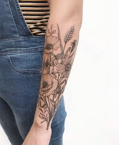 a woman's arm with flowers on it and a striped shirt in the background