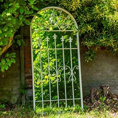 a white iron gate sitting next to a lush green bush