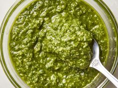 a glass bowl filled with green sauce and a spoon