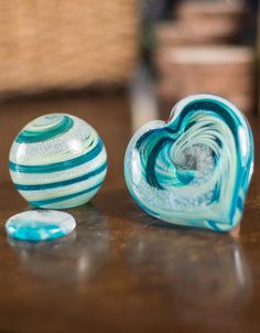 two glass bowls sitting on top of a table next to each other, one blue and the other white