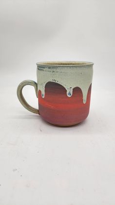 a red and white coffee cup sitting on top of a table