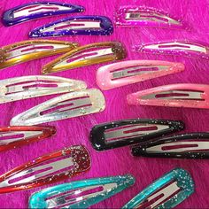 many different colored hair clips laying on top of a pink fur covered floor next to each other