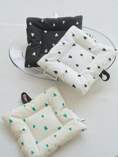 three pillows sitting on top of a table next to a glass plate with a black and white pillow