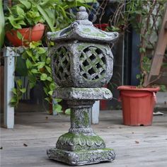 an old stone lantern sitting on top of a wooden floor next to potted plants