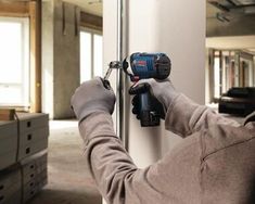 a man is using a drill to fix a door