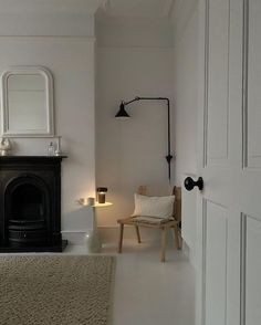 a living room with a chair, fireplace and mirror on the wall next to it