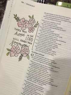 an open bible with pink flowers on it