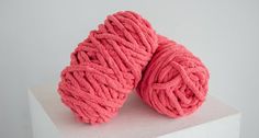 two balls of pink yarn sitting on top of a white block