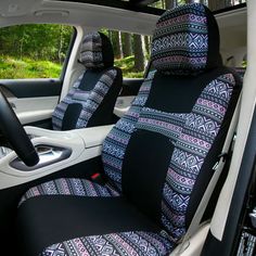 the interior of a car with black and white patterned seat covers on it, in front of trees