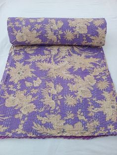 a roll of purple and gold fabric sitting on top of a bed