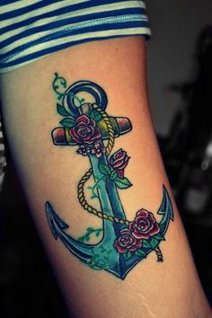 an anchor with roses on the side of her leg is seen in this tattoo design