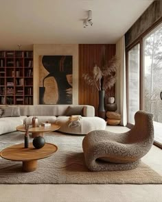 a living room filled with lots of furniture next to large windows and bookshelves