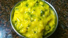 a metal bowl filled with yellow sauce on top of a counter