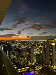 the city skyline is lit up at night with bright lights in the foreground and clouds in the background