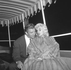 a man and woman sitting on a boat under a awning with their arms around each other