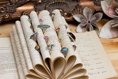 an open book sitting on top of a wooden table next to paper flowers and other items