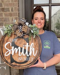 a woman holding a wooden sign that says the smith family on it with succulents