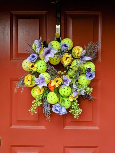 a red door with a green and yellow wreath hanging on it's front door