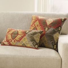 two decorative pillows sit on the back of a couch