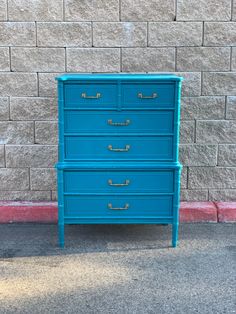 a blue dresser sitting in front of a brick wall