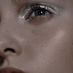 a woman's face with silver glitter on her eyes