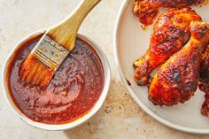 a white plate topped with wings covered in bbq sauce and a wooden spatula