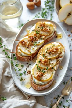 two slices of bread topped with cheese and nuts on a plate next to a glass of water