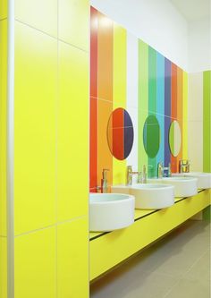 a bathroom with three sinks and rainbow colored walls