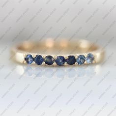 a yellow gold band with blue sapphire stones on the side and white diamonds in the middle