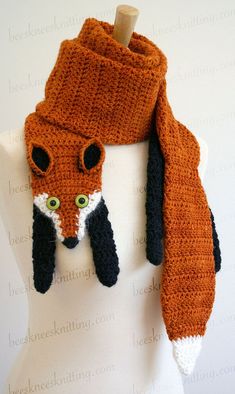 an orange scarf with a black and white fox on it's head is hanging from a mannequin