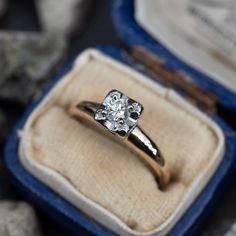 an engagement ring with a diamond in it sitting inside a box next to some rocks