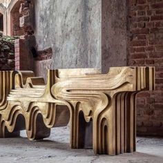 two wooden benches sitting next to each other in front of a brick wall and doorway