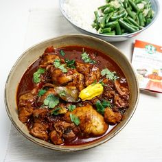 a bowl filled with meat and vegetables next to a box of rice on a table