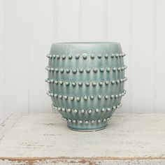 a blue vase sitting on top of a wooden table next to a white painted wall