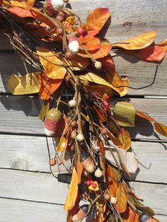 an arrangement of autumn leaves and acorns hangs on a wooden planked wall