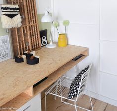 a wooden desk topped with a white chair next to a yellow vase