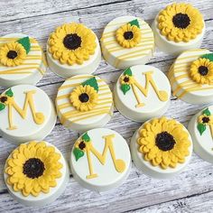 twelve sunflower decorated cupcakes with the letter m on each one, and an initial in the middle