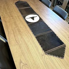 a wooden table with black chairs and a white logo on the edge that is shaped like a tie