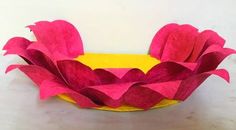 a yellow and pink paper bowl on a white surface with red flowers in the center