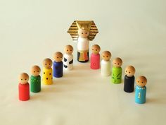 a group of wooden peg dolls standing in front of a nativity scene on a white background